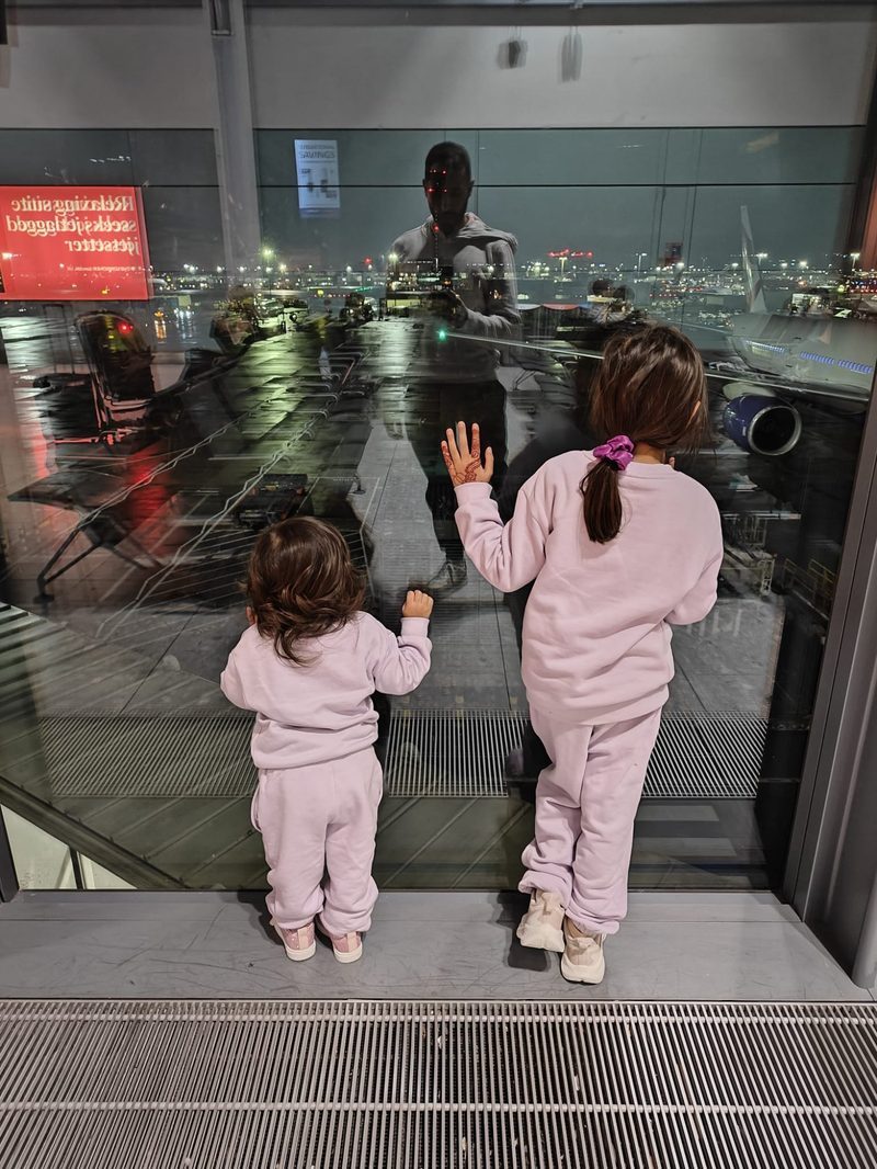 Two young children looking out at planes at the airport — the Little Valet family